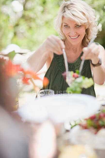 Mulher servindo salada ao ar livre — Fotografia de Stock