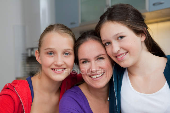 Mutter und Töchter lächeln zusammen, konzentrieren sich auf den Vordergrund — Stockfoto