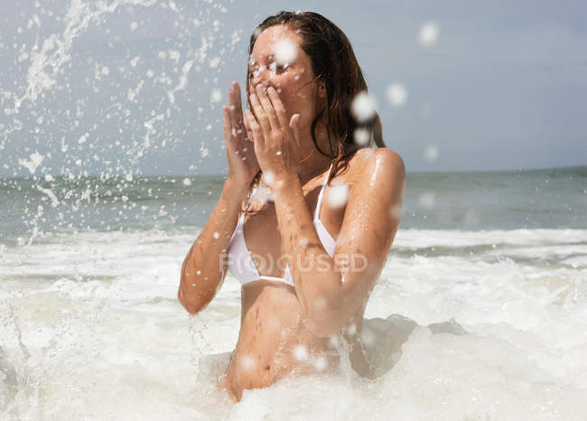 Ragazza che si copre il viso, spruzzi d'acqua — Foto stock
