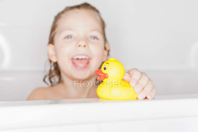 Girl playing with rubber duck in bath — Stock Photo
