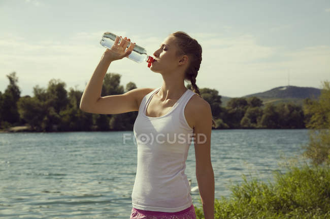 Jovem jogger feminino bebendo água engarrafada — Fotografia de Stock