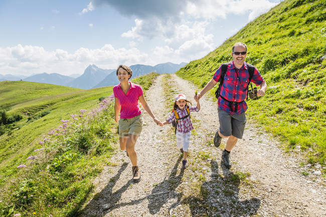 Padres e hija tomados de la mano a pie, Tirol, Austria - foto de stock