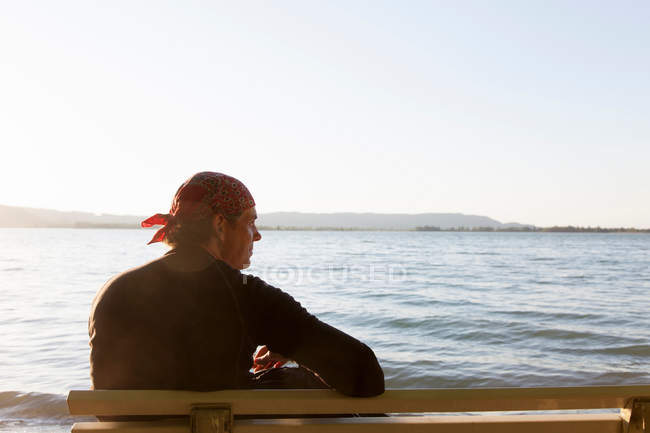 Homem sentado no banco na praia — Fotografia de Stock