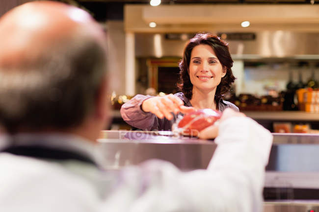Woman buying meat from butcher — Stock Photo