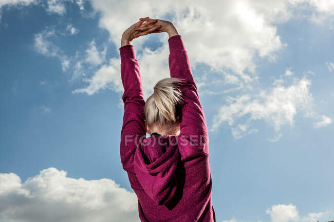 Jeune femme étirant les bras vers le haut — Photo de stock
