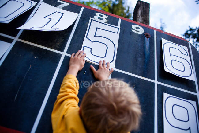 Giovane ragazzo giocare con i numeri sul tabellone segnapunti — Foto stock