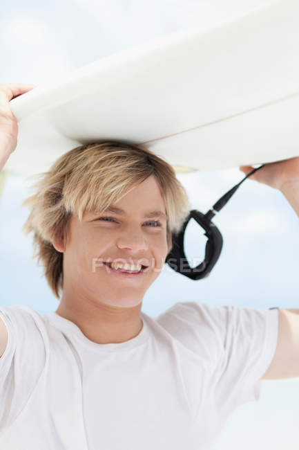 Adolescent garçon portant planche de surf, se concentrer sur le premier plan — Photo de stock