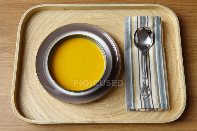 Tablett mit Schüssel Sahnesuppe und Löffel auf Stoffserviette — Stockfoto