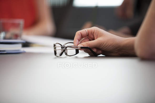 Close up of hand and spectacles at meeting — Stock Photo