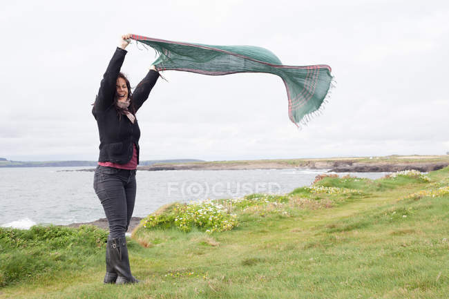Женщина играет с шарфом на травянистом поле — стоковое фото