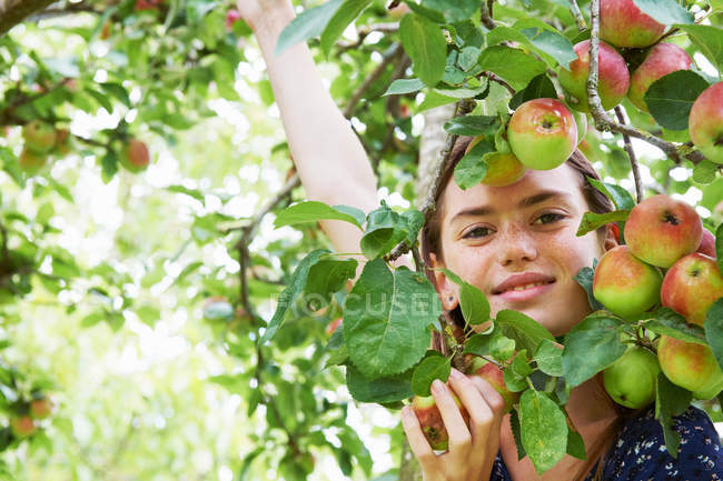 Sorrindo menina brincando na árvore de frutas — Fotografia de Stock