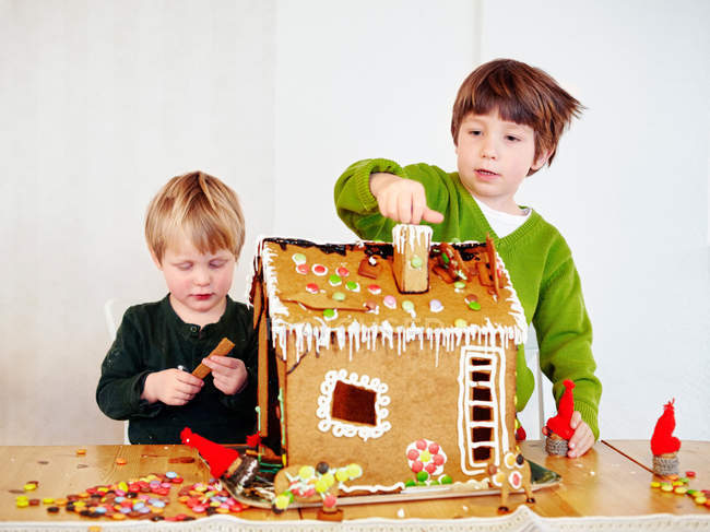 Jungen dekorieren Lebkuchenhaus — Stockfoto