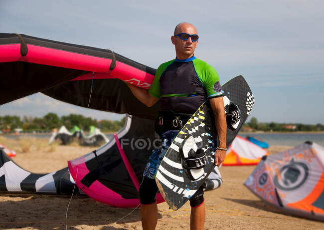 Kitesurfer sosteniendo cometa y tabla - foto de stock