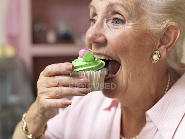 Seniorin genießt Cupcake im Café — Stockfoto