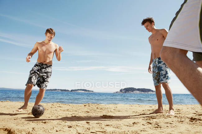 Чоловіки грають у футбол на пляжі — стокове фото