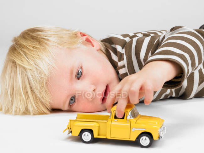 Маленький хлопчик грає з жовтою вантажівкою — стокове фото