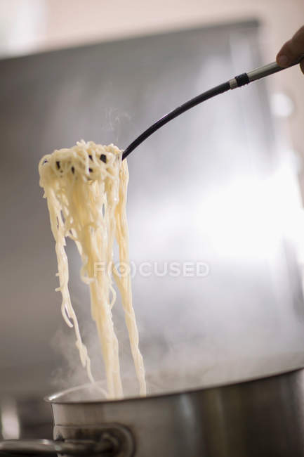 Обрізане зображення шеф-кухаря, який готує макарони на кухні — стокове фото