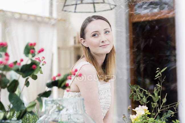 Blick durch Blumenfenster und wegschauende Frau — Stockfoto