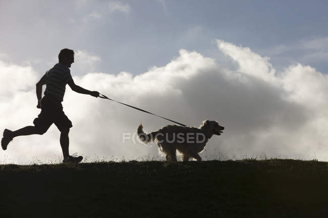 Hombre corriendo con perro en plomo - foto de stock