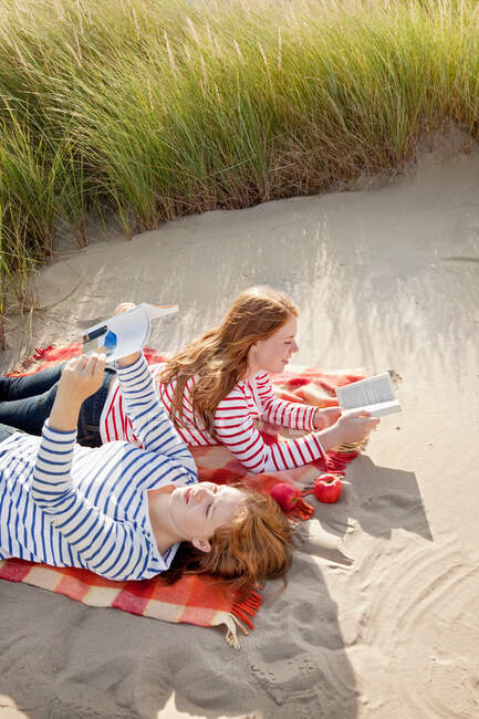 Dos adolescentes listos libros en las dunas - foto de stock