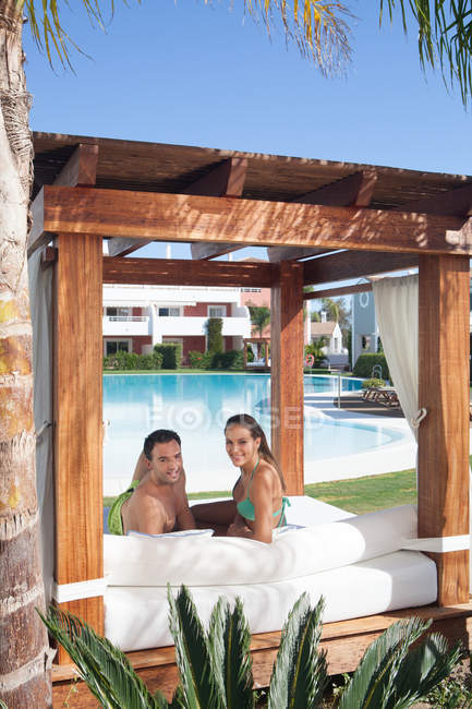 Casal jovem relaxante na espreguiçadeira no resort de férias — Fotografia de Stock