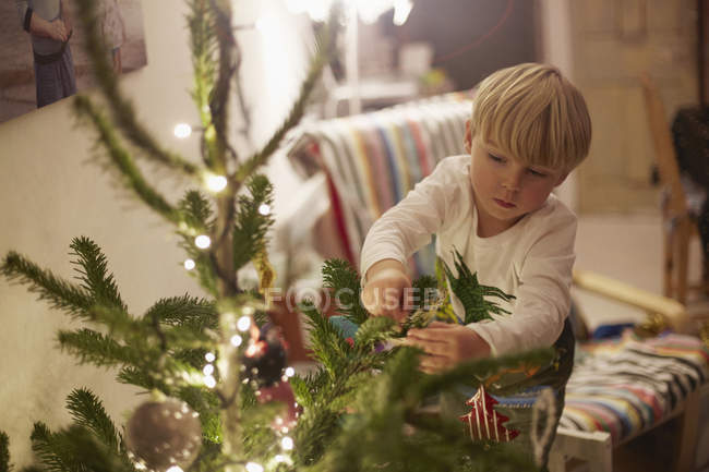 Junge schmückt Baum zu Weihnachten — Stockfoto