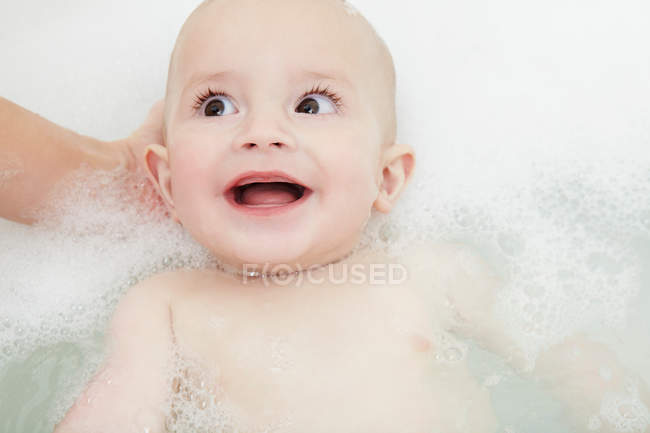 Mother washing baby girl in bubble bath — Stock Photo