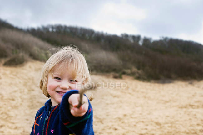 Хлопчик на пляжі, вказуючи палицею — стокове фото