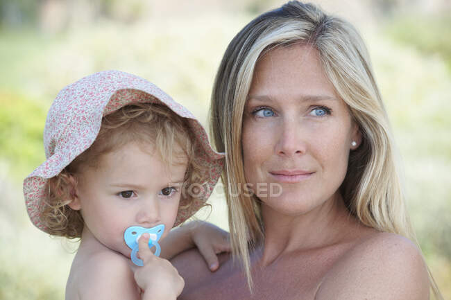 Mãe abraçando criança usando chapéu de sol — Fotografia de Stock