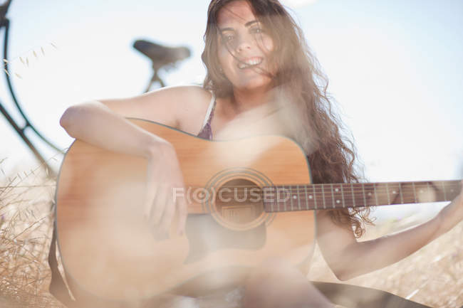 Женщина играет на гитаре в высокой траве — стоковое фото
