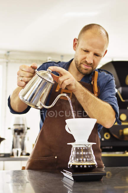 Barista pouring boiling water in coffee filter — Stock Photo