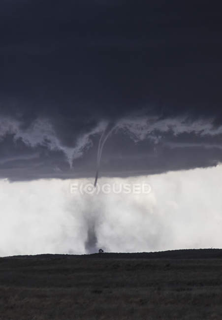 Thin tornado with funnel cloud touches down over rural prairie — Stock Photo