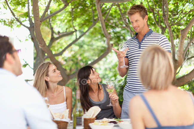 Друзі п'ють вино за столом на відкритому повітрі — стокове фото