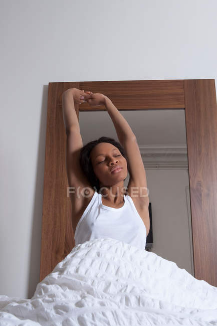 Frau dehnt sich im Bett, Fokus auf Vordergrund — Stockfoto