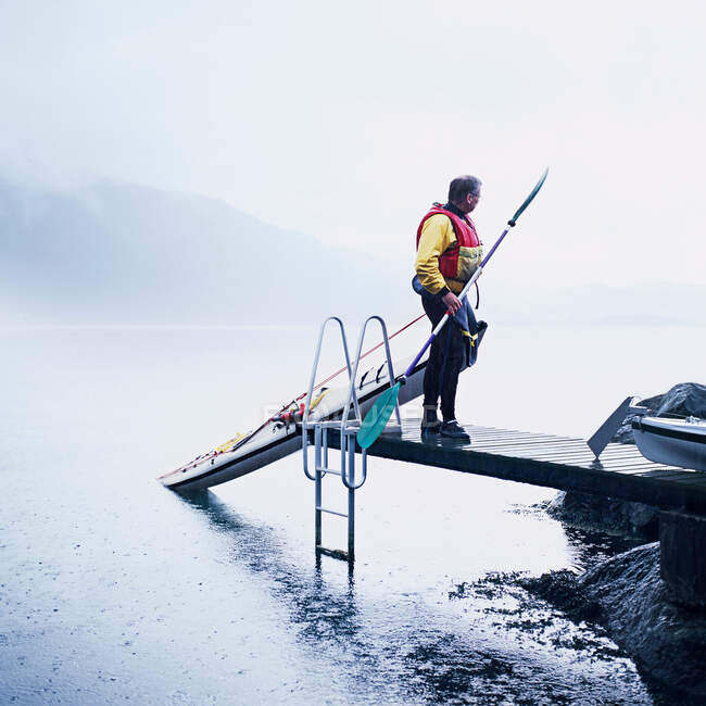 Hombre tirando de kayak en el muelle - foto de stock