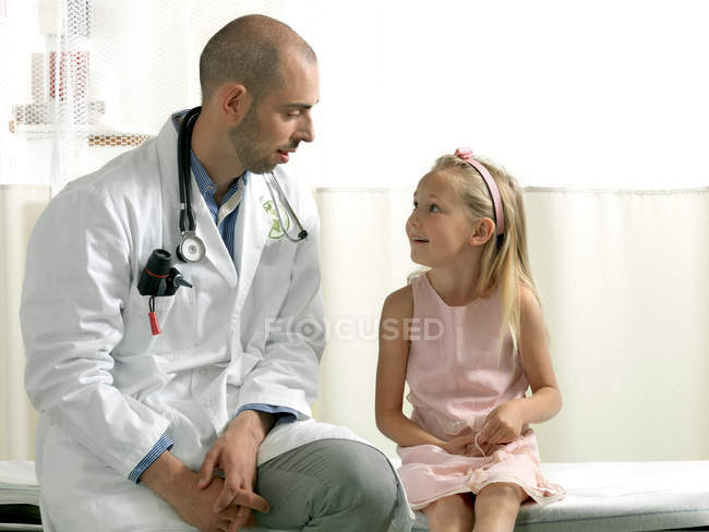 Doctor consulting girl in clinic — Stock Photo