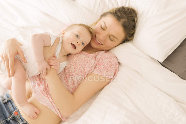 Мать и ребенок сближаются на кровати дома — стоковое фото