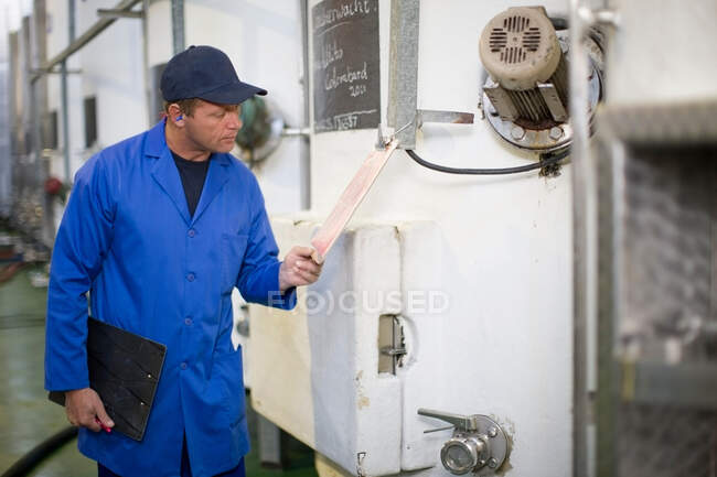 Worker reading clipboard in factory — Stock Photo