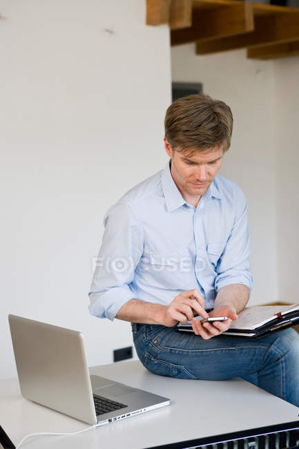 Homme d'affaires utilisant un téléphone portable au bureau — Photo de stock