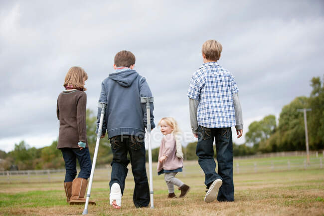 Junge auf Krücken mit anderen Kindern — Stockfoto