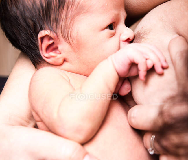 Close up of baby boy breastfeeding from mid adult mother — Stock Photo