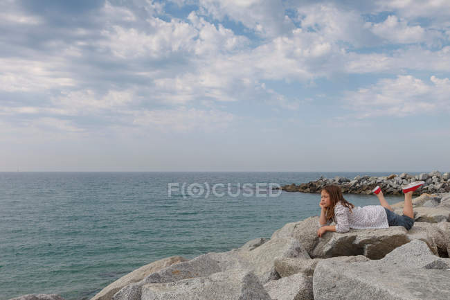 Girl relaxing on rocky beach — Stock Photo