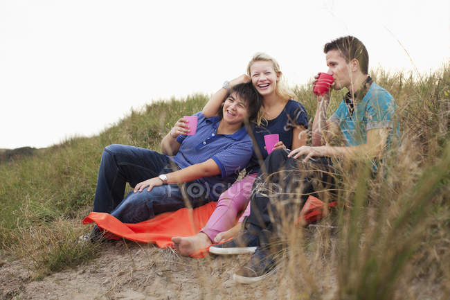 Teenagers sitting on bin bag with drinks — Stock Photo