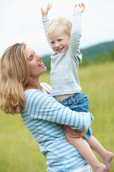 Woman holding cheering son outdoors — Stock Photo