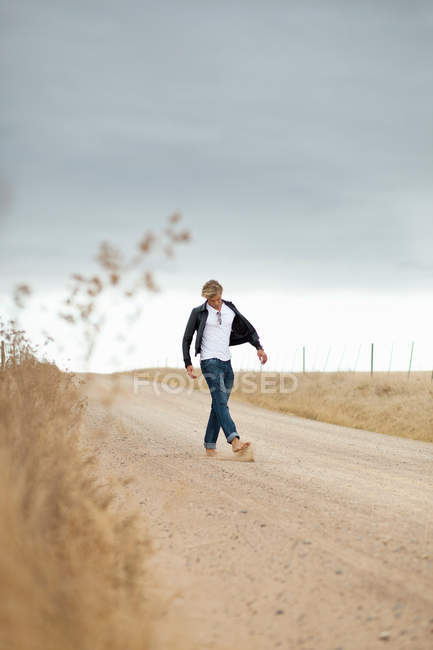 Rapaz chutando pedra na estrada — Fotografia de Stock