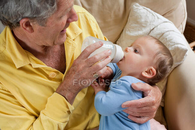 Дедушка кормит внука молочной бутылкой — стоковое фото