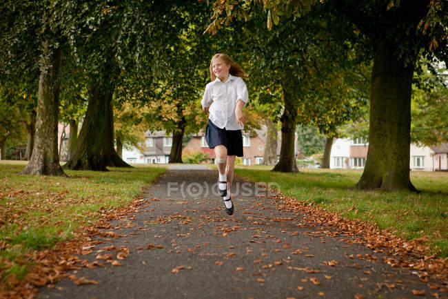 Girl skipping on road in park, focus on foreground — Stock Photo