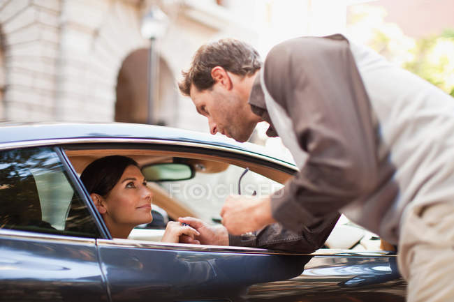 Чоловік розмовляє з жінкою через вікно автомобіля — стокове фото