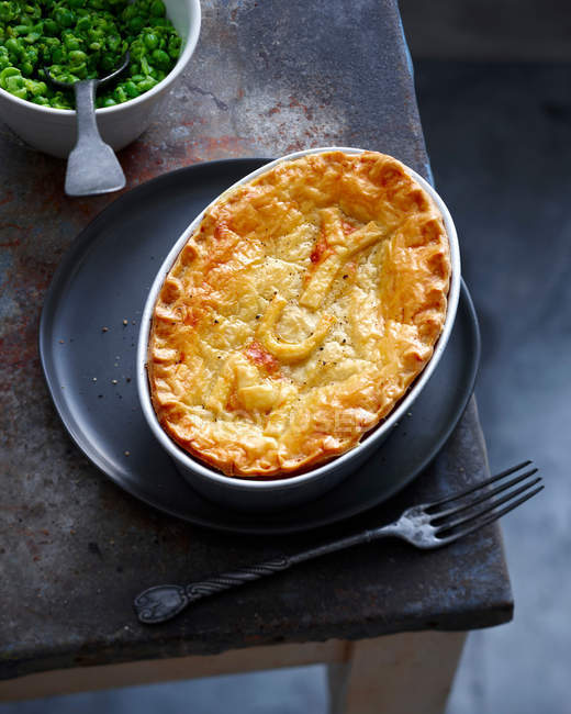 Dish of baked pie and peas — Stock Photo