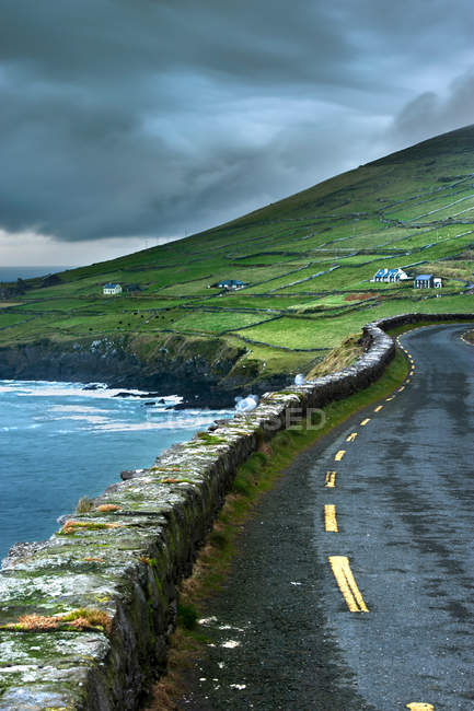 Paved road along green rural cliffs — Stock Photo